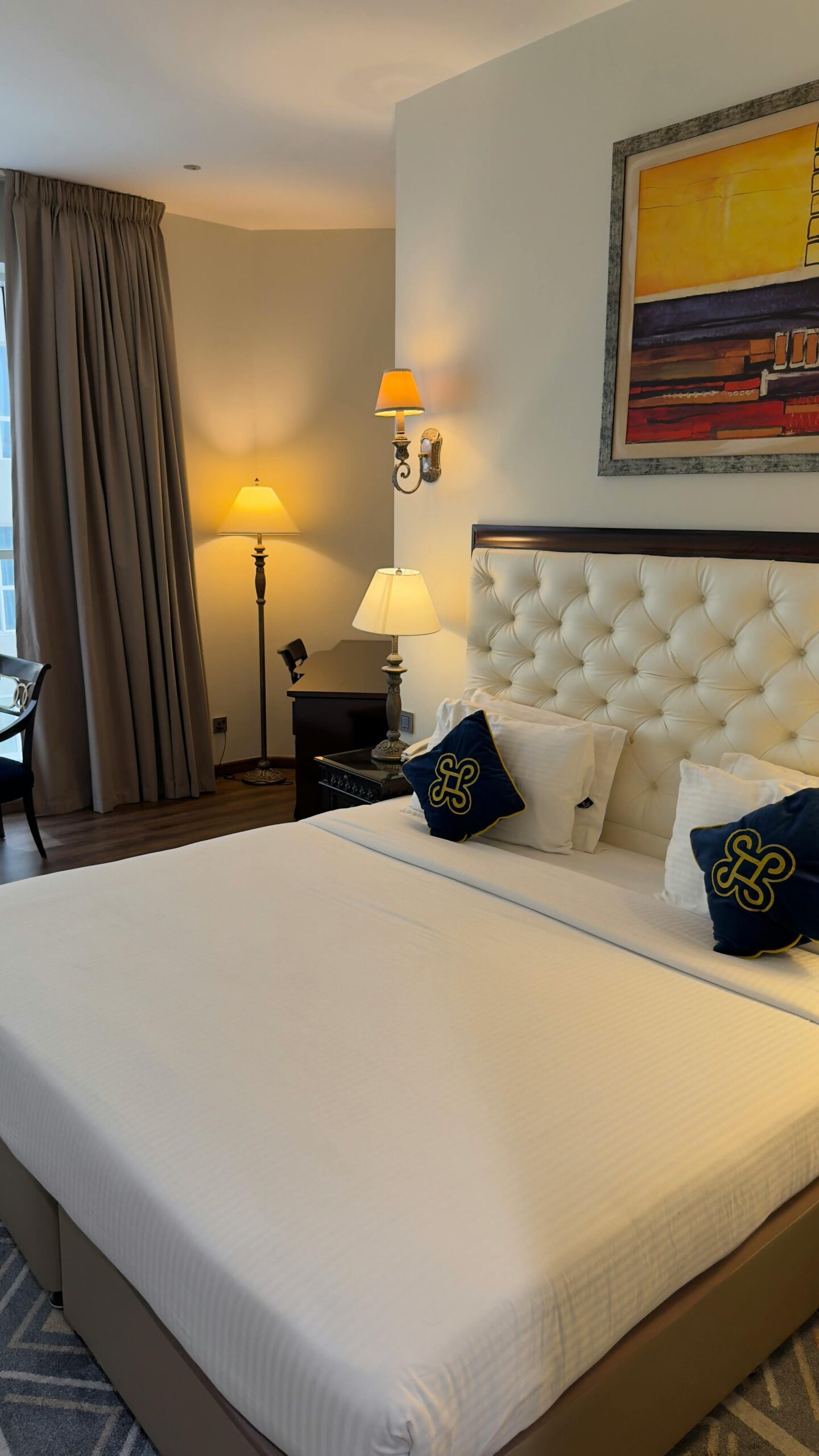 Cozy hotel room featuring a plush bed, artistic decor, warm lighting, and stylish furnishings.